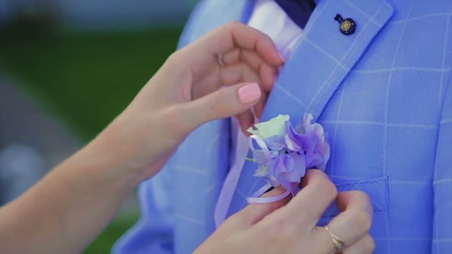 Close up of a Woman Pinning Boutonniere on Man
