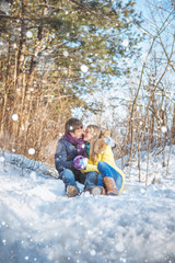 Fototapeta na wymiar A loving couple walking in winter park. The snowfall