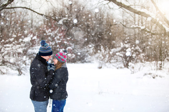 Loving couple embracing in winter park. Loving warm hands to each other. Copy space. The girl hat with red hearts