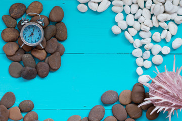 Summer concept : Seashells and pebble with alarm clock on wood b