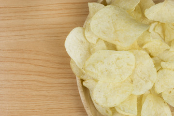 potato chips in wood plate on wood table.