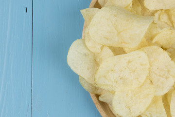potato chips in wood plate on wood table.