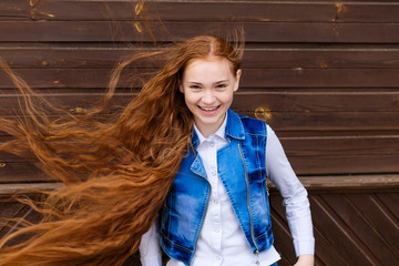 Portrait of beautiful smiling redhead girl with long hair fluttering in the wind