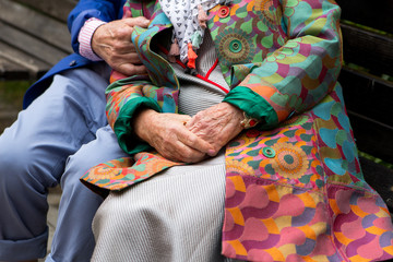 Elderly couple sitting on a bench. Hands close-up.