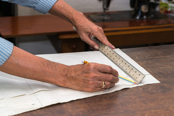 dressmaker drawing tailor pattern with pencil for a suit on the table
