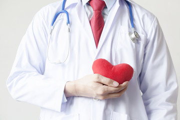 Doctor showing compassion and support holding red heart onto his