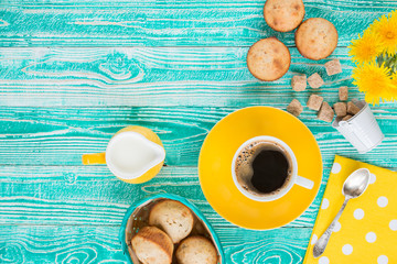 cup of coffee on yellow plate and yellow milk jug cane sugar, notebook, pen, cakes, teaspoon on...