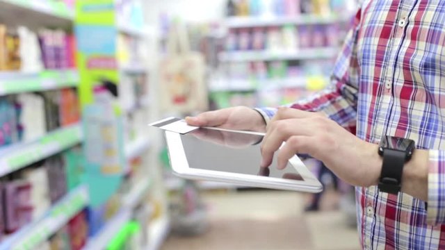 Man Using Phone and Credit Card in Store