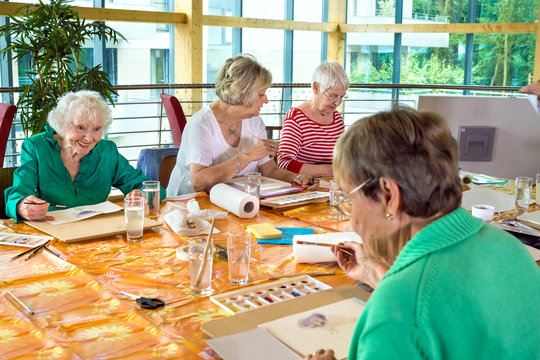 Group Of Cheerful Older Students Painting Together.