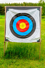 Outdoor archery targets on grass field surrounded by forest in the summer evening.