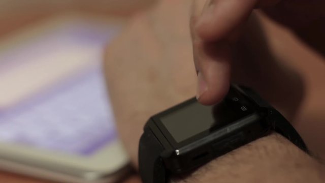 Man Uses a Smart Watch and Tablet
