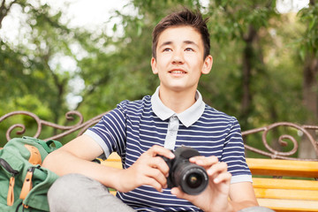 happy teenager boy with a camera in hand, in the summer park © olezzo