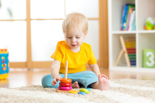 Preschooler child playing with colorful toy. Kid playing with educational wooden toy at kindergarten or daycare center. Toddler in nursery.