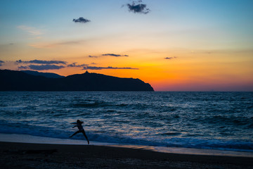 Sunrise at Tinderi beach with a girl jumping in the foreground