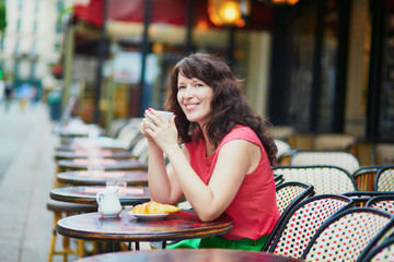 woman drinking coffee and eating croissant