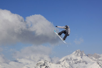 Naklejka na ściany i meble Snowboard rider jumping on mountains. Extreme snowboard freeride sport.