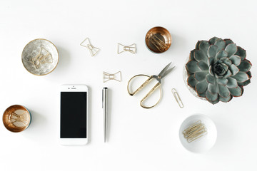 feminini desk workspace with succulent, phone, scissors and golden clips on white background. flat lay, top view