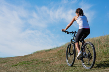 Fototapeta premium Sport bike woman on the meadow with a beautiful landscape