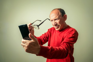 portrait of the funny senior man looking on phone