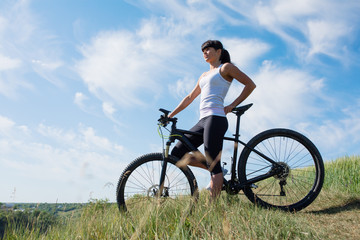 Fototapeta premium Sport bike woman on the meadow with a beautiful landscape