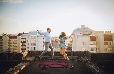 Young couple having fun on the gray roof of apartment building in residential Area