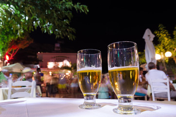 Two glasses of beer on a table.