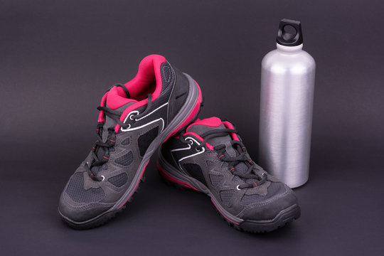 Women's hiking boots and water bottle on black background