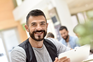 Trendy businessman in office working on tablet