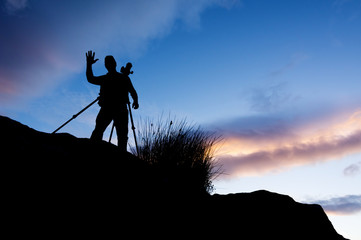  photographer  silhouette on the rocks in the mountains with dramatic sky at dusk