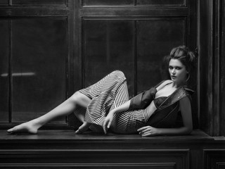 Tall model lying on the windowsill in dark midi leather jacket