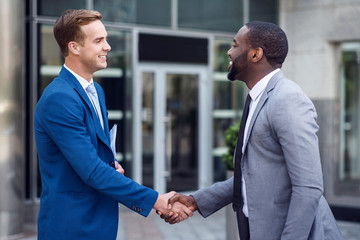 Pleasant colleagues shaking hands