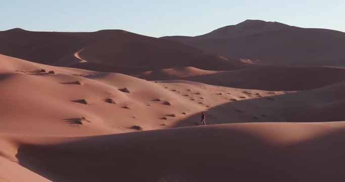 4K panning up shot of male tourist walking on the sand dunes inside the Namib-Naukluft National Park 