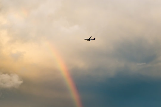 Airplane flying in rainbow sky.