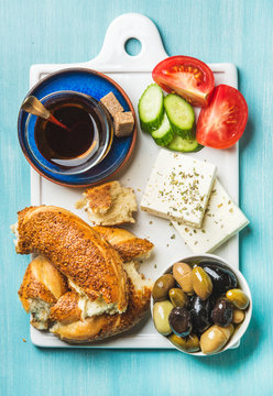 Turkish traditional breakfast with feta cheese, vegetables, olives, simit bagel and tea