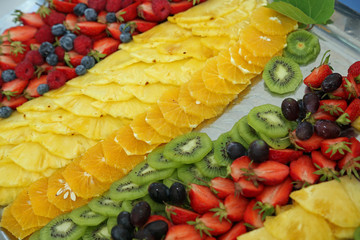 Fototapeta na wymiar Platte mit Ananas, Kiwi, Erdbeeren und Orangen