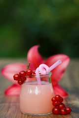 jar with pink grapefruit cocktail on green background bokeh