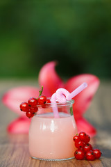 jar with pink grapefruit cocktail on green background bokeh