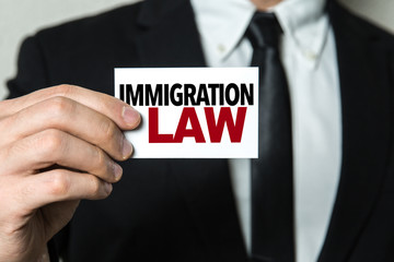 Business man holding a card with the text: Immigration Law