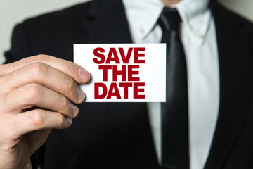 Business man holding a card with the text: Save the Date