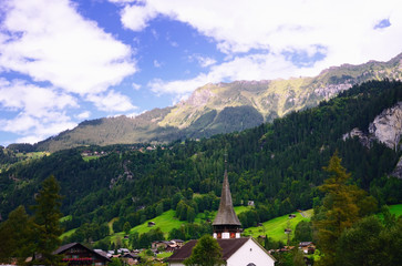 Fototapeta na wymiar Tourist Town of Lauterbrunnen in Lauterbrunnen Valley (Jungfrau Region, Switzerland). Church in the Foreground. Mountain Slopes in the Background.