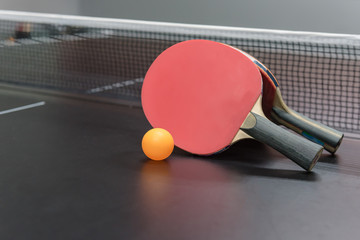 orange ball with red table tennis racket on black table