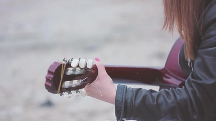 A girl playing guitar on the wild beach