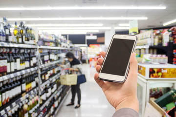 hand holding mobile phone on Supermarket blur background, business concept