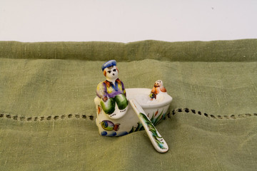 Fototapeta premium Open castor in Russian primitive style with figures of man and cat on green linen tablecloth.