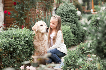 Cute baby girl 3-4 year old holding labrador pet outdoors. Togetherness. Friendship.