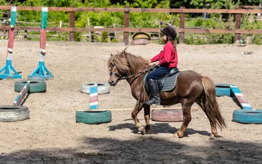 Foto op Canvas little girl is riding a horse © Olexandr