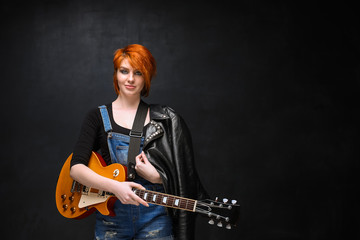 Portrait of young girl with guitar over black background.