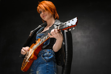 Portrait of young girl with guitar over black background.