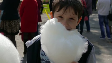 boy son eating cotton candy at the park in summer