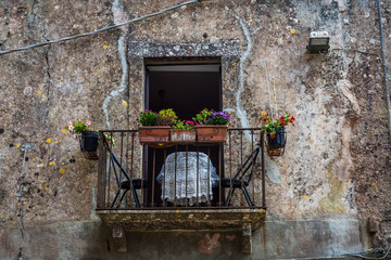 Fototapeta na wymiar Old balcony with chairs and table at Erice, Sicily